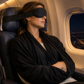 Woman asleep upright on a night flight wearing the Norrow sleep set (illustration)